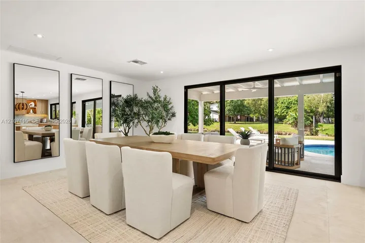 Open-concept interior featuring large-format tile flooring, recessed lighting, expansive multi-panel sliding glass doors, and three floor-to-ceiling wall mirrors