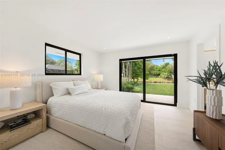 Suite Bedroom 1 ,Bright interior featuring neutral walls, large sliding glass doors, black-framed windows, and light-toned flooring