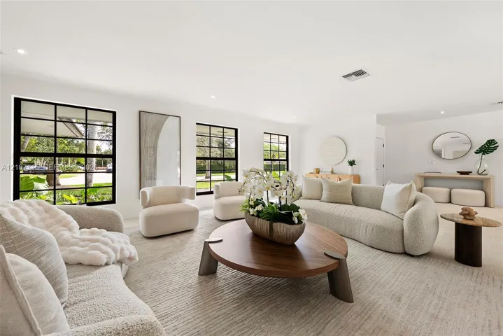 Open-concept living space featuring expansive windows with black mullions, recessed ceiling lighting, and neutral-toned wall-to-wall carpeting