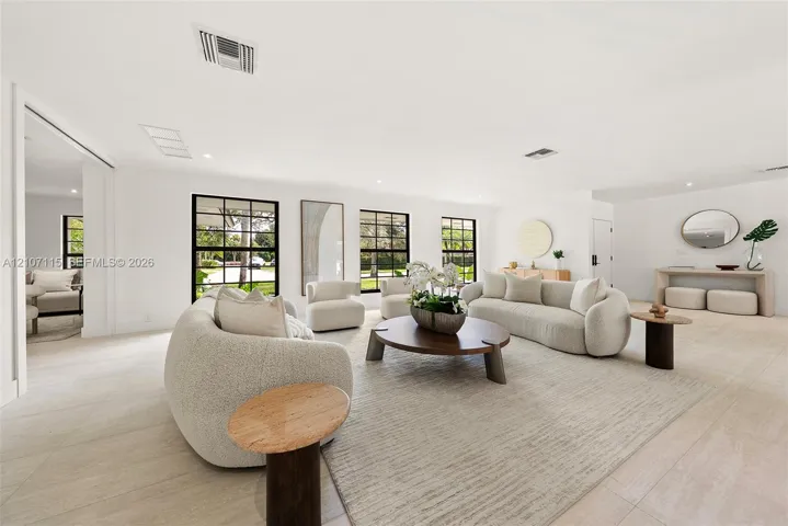 Open-concept interior featuring light-toned flooring, expansive grid-pattern windows with dark frames, and recessed lighting