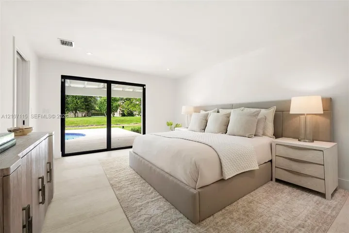 Spacious room featuring floor-to-ceiling sliding glass doors, neutral tile flooring, and recessed lighting