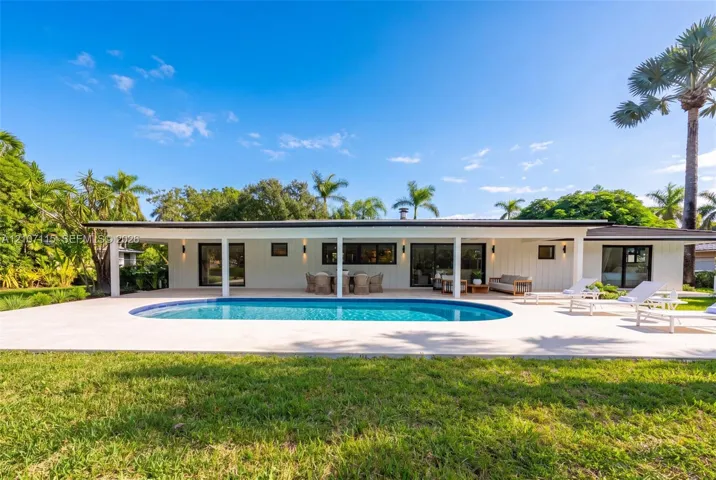 Expansive rear patio featuring a swimming pool, covered lanai, vertical exterior siding, and sliding glass​​‌​​​​‌​​‌‌​‌‌​​​‌‌​‌​‌​‌​​​‌​​ doors