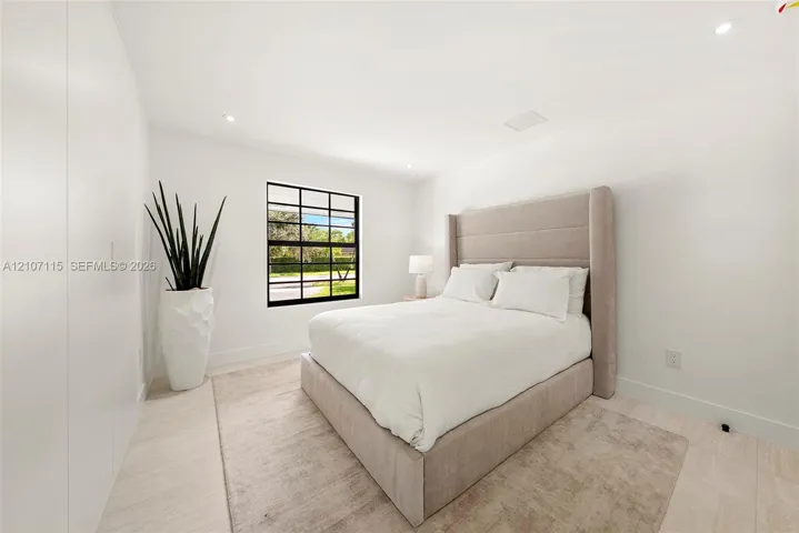Bedroom 3 Minimalist room featuring smooth white walls, recessed ceiling lighting, light-toned tile flooring, and a black-framed grid window