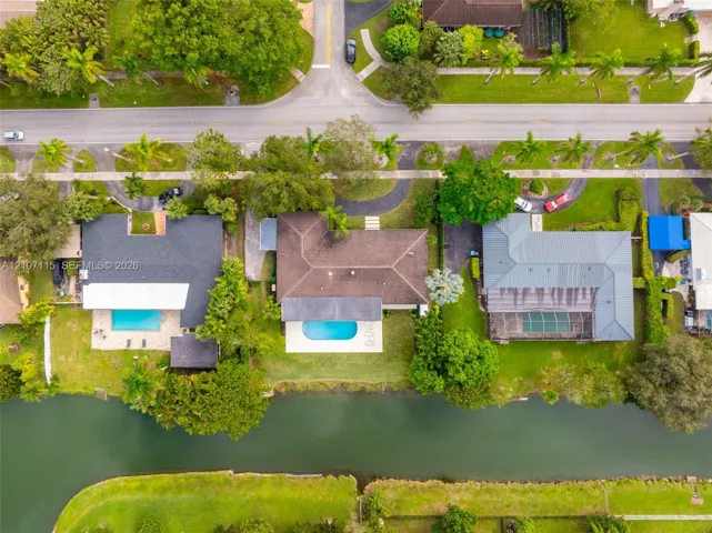 Aerial perspective of waterfront properties featuring swimming pools, lush landscaping, and direct canal access