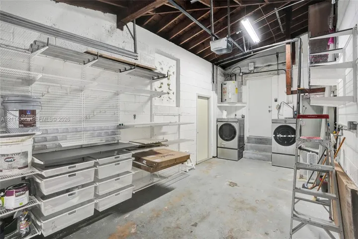 Utility area featuring built-in wire shelving, integrated storage bins, exposed ceiling beams, and concrete flooring
