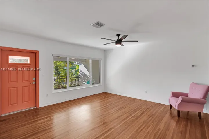 Interior space featuring wood-finish flooring, a large picture window, a ceiling-mounted light fixture with fan, and a paneled exterior door