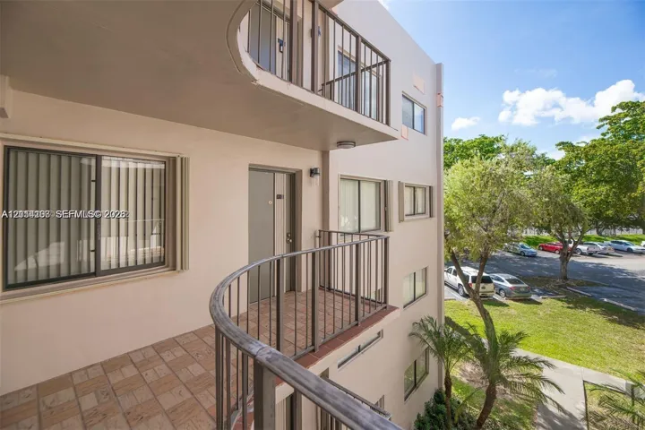 Multi-story exterior featuring a private curved balcony with tiled flooring and metal railings, complemented by sliding glass windows