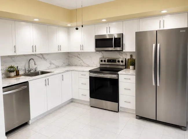 Kitchen featuring white shaker-style cabinetry, stone-patterned backsplash, stainless steel appliances, and solid surface countertops