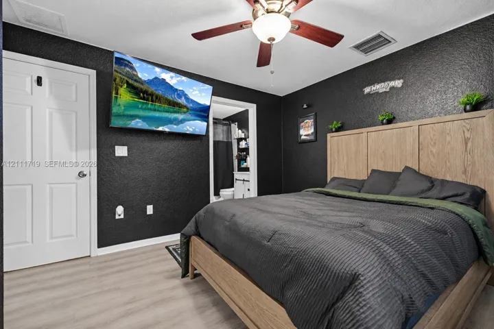 Textured charcoal-painted walls, light wood-finish flooring, and a ceiling fan with integrated lighting