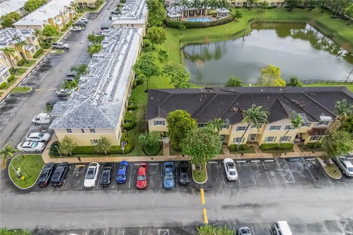 Aerial perspective of multi-unit residential buildings featuring dark-toned tile roofing, exterior stucco finishes, and dedicated surface parking
