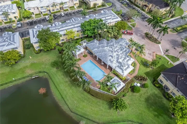 Aerial perspective of a multi-story residence featuring a private swimming pool, paved patio, detached pergola, and waterfront positioning