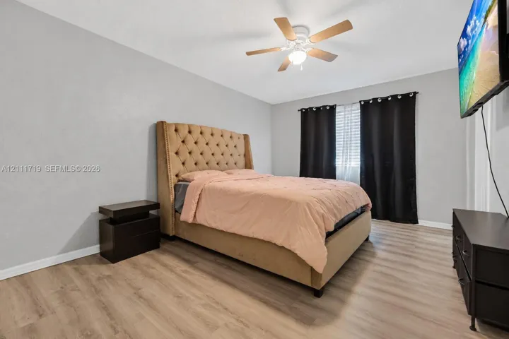 Neutral wall tones, wood-finish flooring, and a ceiling fan with integrated lighting
