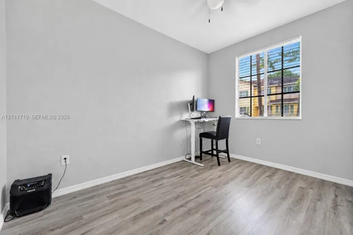 Room featuring neutral-toned walls, wood-finish flooring, a multi-pane window with a grid pattern, and a ceiling-mounted light fixture