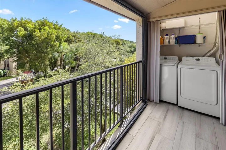 Balcony featuring black metal railing, wood-finish tile flooring, and integrated laundry area with wire shelving