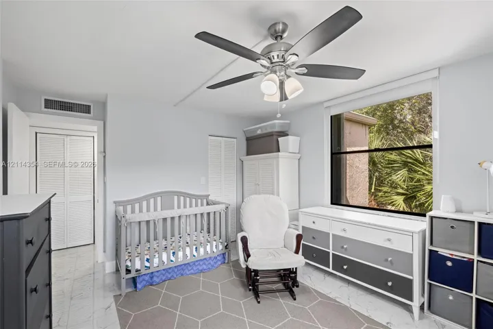 Room featuring large-format tile flooring, a multi-blade ceiling fan with integrated lighting, and louvered closet doors