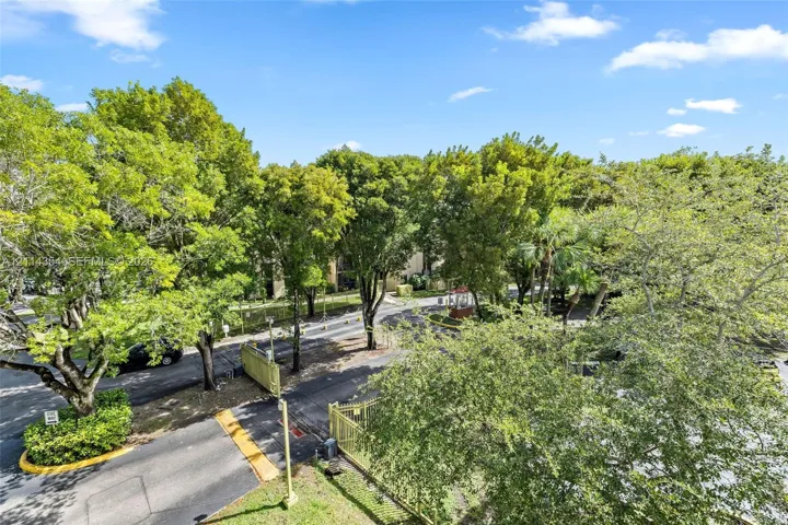 Expansive grounds featuring mature trees, paved driveways, and perimeter fencing