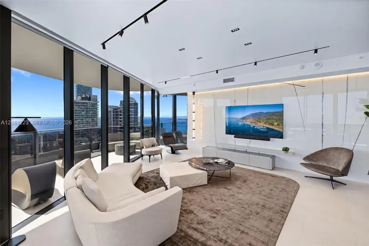 Floor-to-ceiling glass walls, large-format tile flooring, integrated track lighting, and a polished stone feature wall with a floating media console