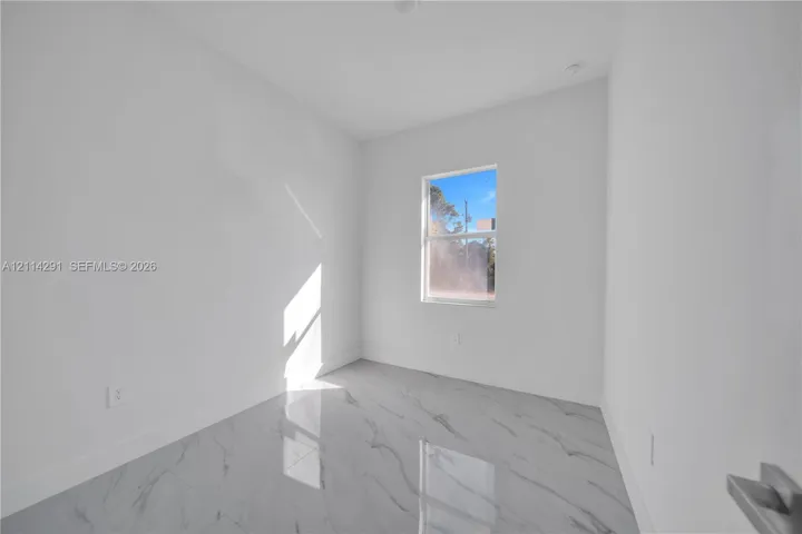 Neutral-toned room featuring large-format tile flooring with a subtle veining pattern and a single-pane window