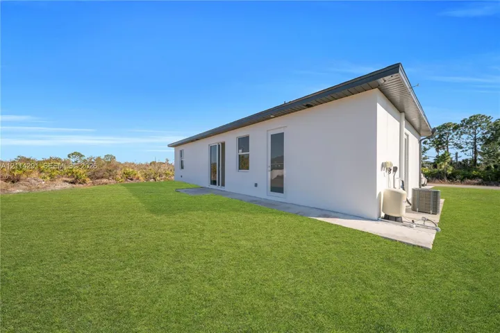 Stucco exterior with a single-slope roof, concrete patio, and manicured lawn