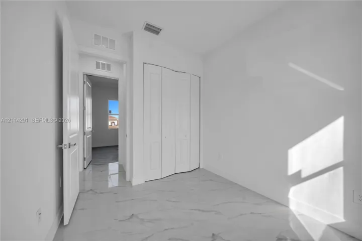 Neutral interior featuring polished large-format tile flooring and white panel-style closet doors