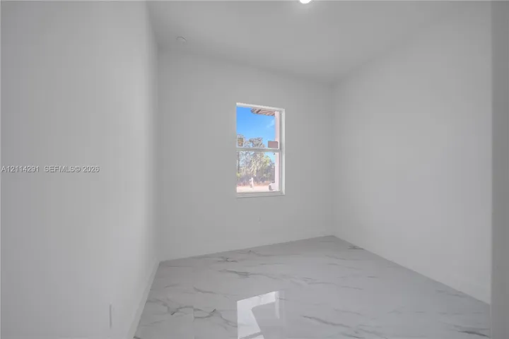 Neutral-toned room featuring large-format tile flooring with a veined finish and a single-pane window