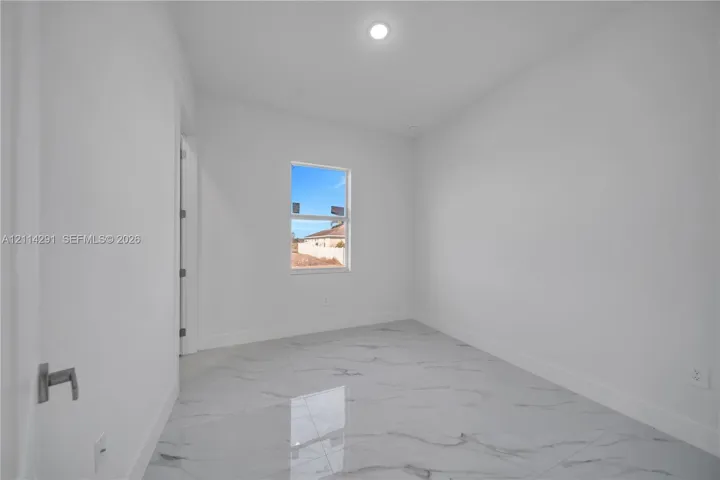 Interior room featuring large-format tile flooring with a neutral veined pattern, recessed ceiling lighting, and a single-pane window