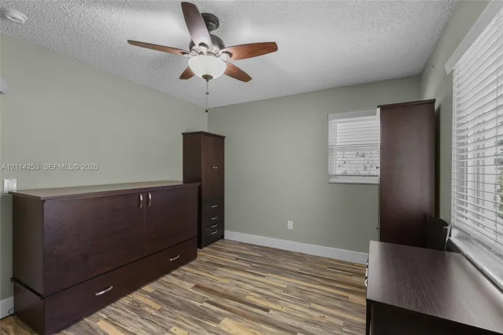 Wood-finish flooring, ceiling fan with integrated lighting, and horizontal window blinds
