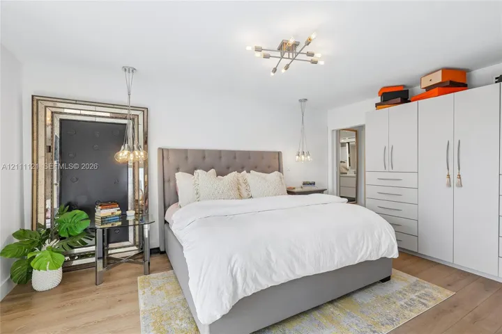 Floor-to-ceiling built-in cabinetry, wide-plank wood-finish flooring, multi-arm ceiling fixture, and dual pendant lights