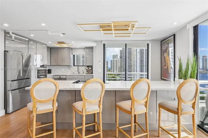 Kitchen featuring a central island with a stone-surface countertop, high-gloss cabinetry, stainless steel appliances, and contemporary geometric ceiling lighting