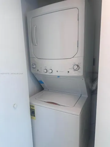 Stackable white laundry unit featuring a top-load washer and front-load dryer configuration