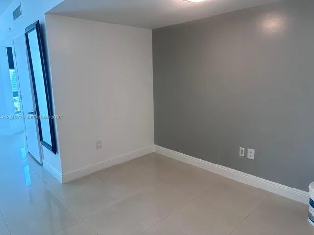 Neutral-toned interior space featuring light-colored large-format tile flooring and a contrasting grey accent wall