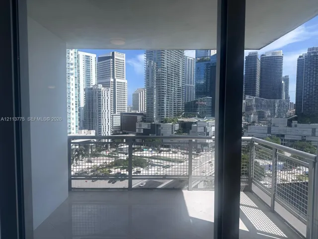 Covered outdoor balcony featuring neutral tile flooring, metal wire mesh railings, and a direct perspective of the urban skyline