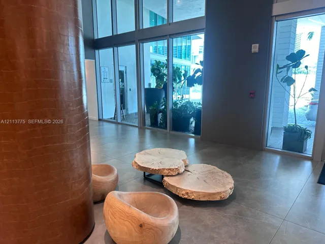 Lobby area featuring floor-to-ceiling glass paneling, expansive tiled flooring, and a textured, cylindrical architectural column