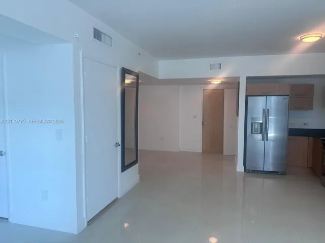 Interior space featuring polished tile flooring, stainless steel side-by-side refrigerator, wood-finish cabinetry, and recessed ceiling lighting