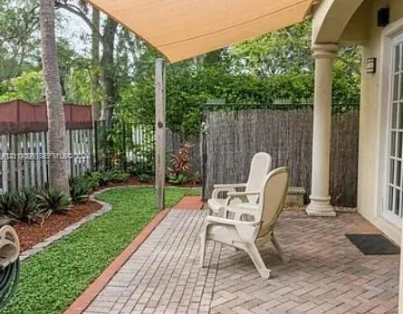 Covered brick paver patio featuring a fabric shade sail and a classic architectural column