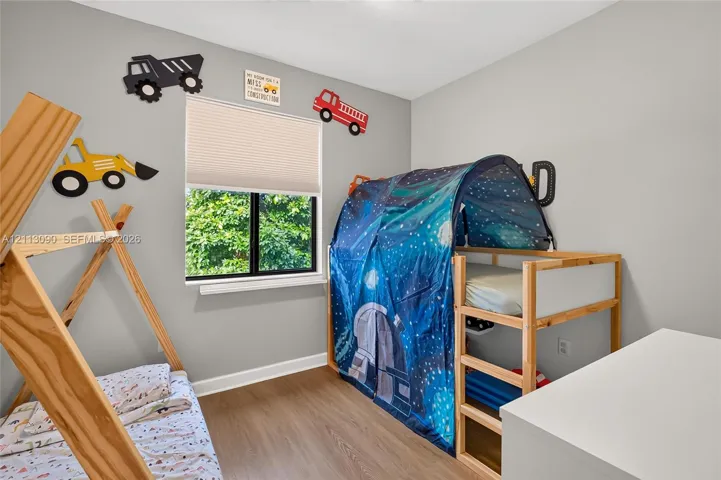 Room featuring wood-finish flooring, neutral wall paint, and a single-hung window with a cellular shade