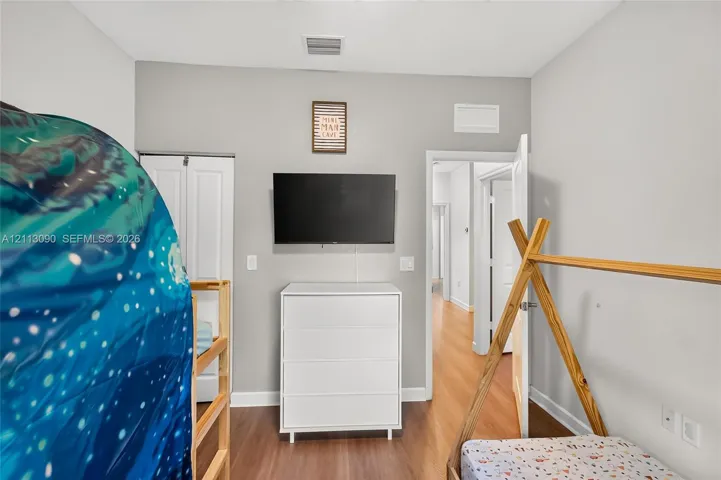 Room featuring neutral-toned walls, wood-finish flooring, and a double-door reach-in closet