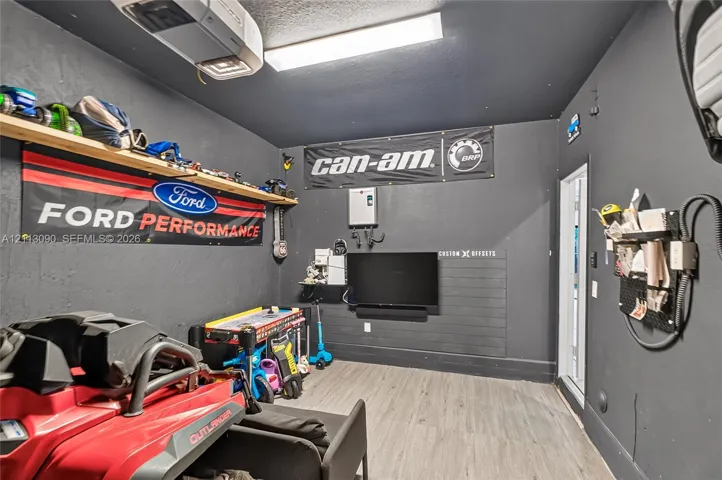 Finished garage space featuring wood-finish flooring, matte dark wall finishes, and integrated wall-mounted storage panels