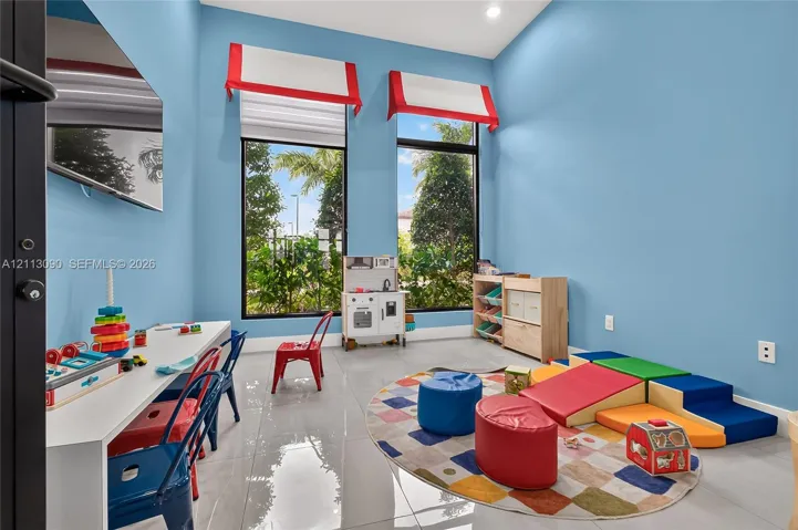 High-ceilinged room featuring large, floor-to-ceiling windows, polished tile flooring, and recessed lighting