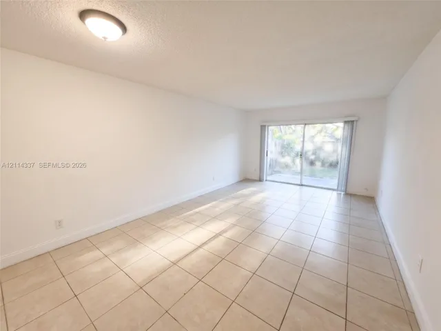 Interior space featuring large-format ceramic tile flooring, neutral wall finishes, a ceiling-mounted flush light fixture, and sliding glass doors