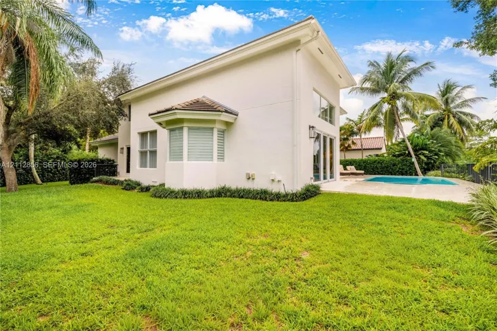 Stucco exterior featuring a bay window, expansive lawn, swimming pool with concrete decking, and floor-to-ceiling glass panel​​‌​​​​‌​​‌‌​‌‌​​​‌‌​‌​‌​‌​​​‌​​ doors