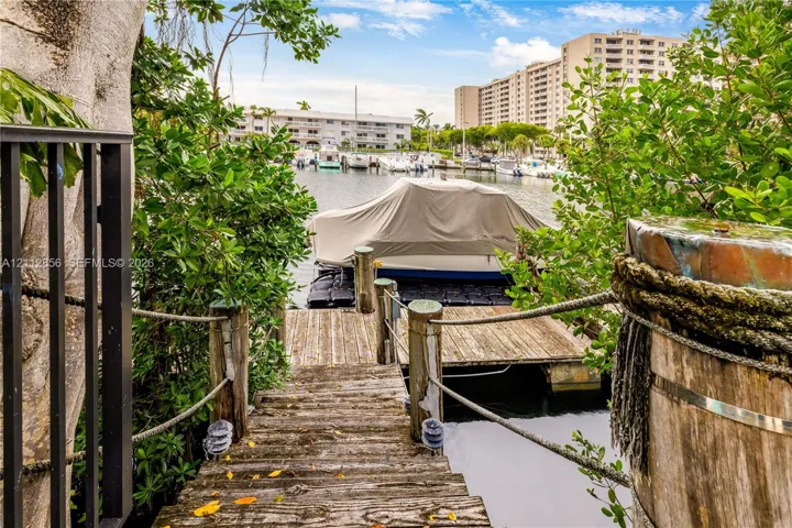 Private wooden dock featuring rope handrails, timber pilings, and direct water access
