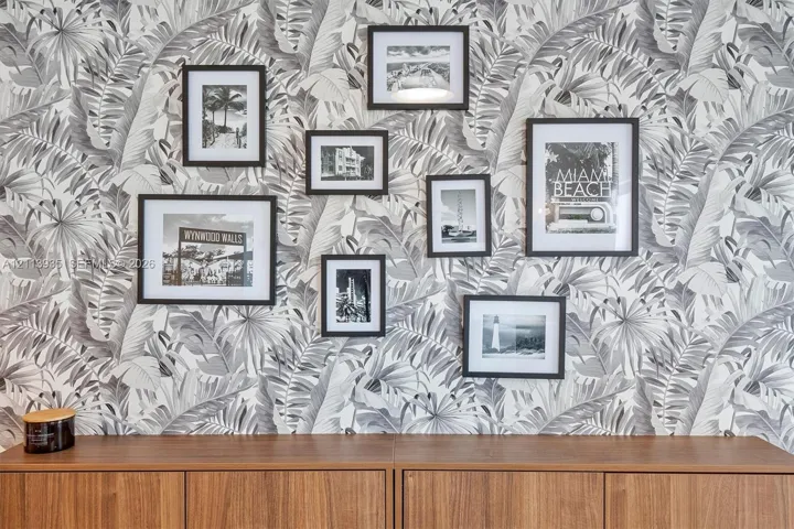 Wall surface featuring monochrome botanical-patterned wallpaper and custom built-in cabinetry with wood finish