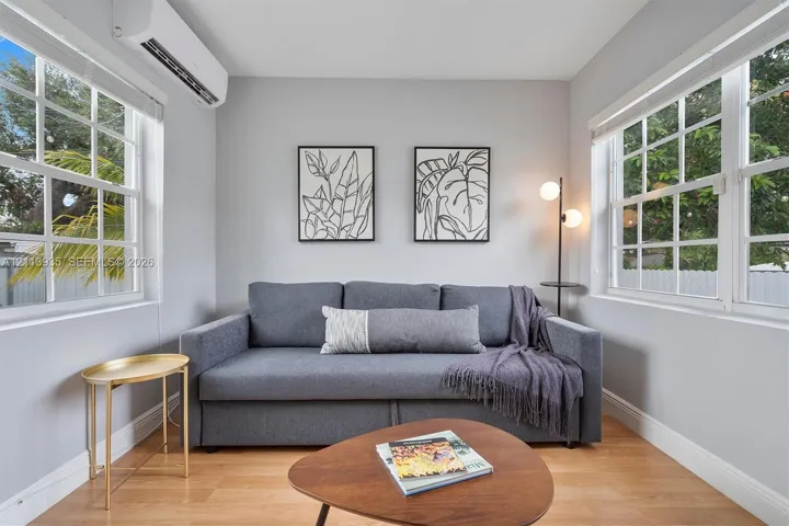 Room featuring wood-finish flooring, dual grid-style windows, and wall-mounted ductless climate control unit