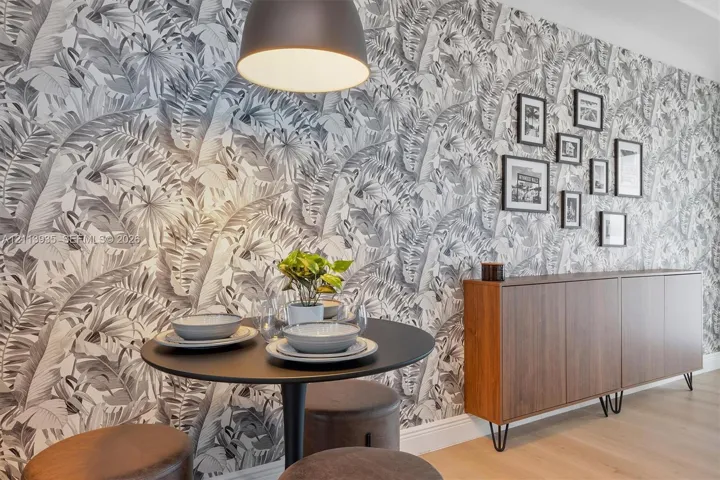 Botanical-print feature wallpaper, custom built-in wood-finish cabinetry, wide-plank wood-finish flooring, and a dome-style pendant light fixture