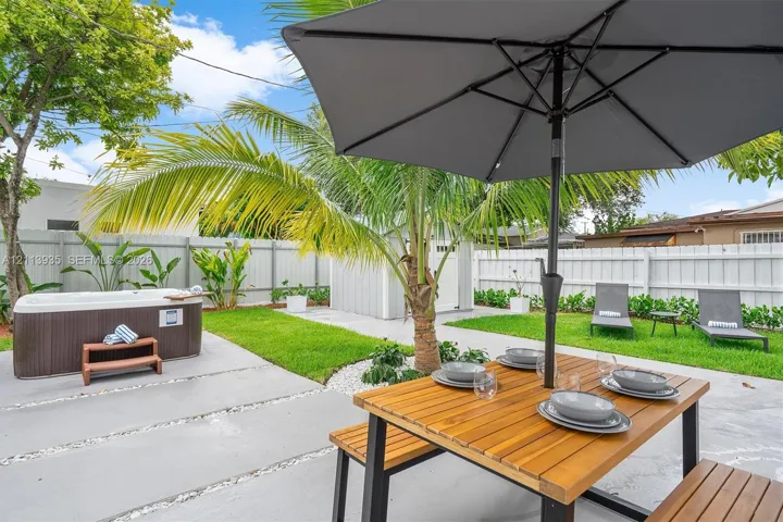Backyard featuring a concrete paver patio, a freestanding hot tub, manicured lawn, white privacy fencing, and a detached storage shed