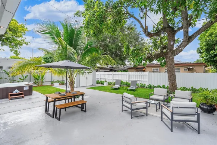 Expansive backyard featuring a concrete patio, a detached storage shed, a hot tub, and vinyl perimeter fencing