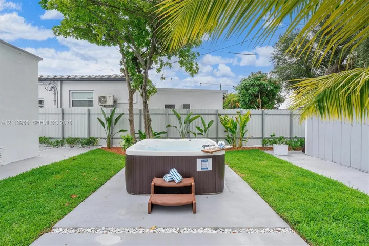 Outdoor space featuring a spa, concrete patio, grass lawn, and perimeter privacy fencing