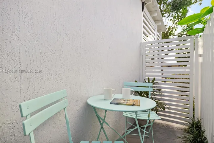 Outdoor area featuring a textured stucco exterior wall and white horizontal slat privacy fencing