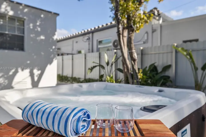In-ground spa with molded seating and wood-finish exterior paneling, enclosed by high privacy fencing